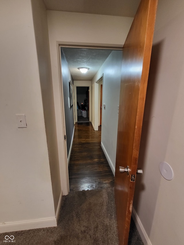 hallway with a textured ceiling and dark hardwood / wood-style floors