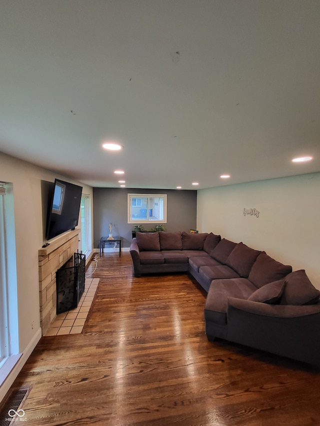 living room featuring a tiled fireplace and hardwood / wood-style flooring