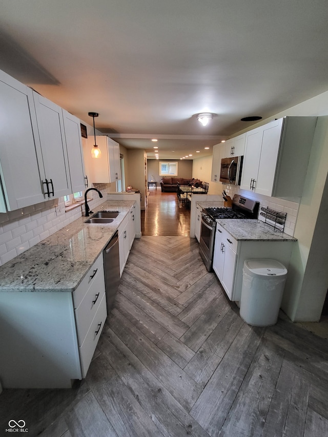 kitchen featuring dark parquet floors, decorative light fixtures, sink, white cabinets, and appliances with stainless steel finishes