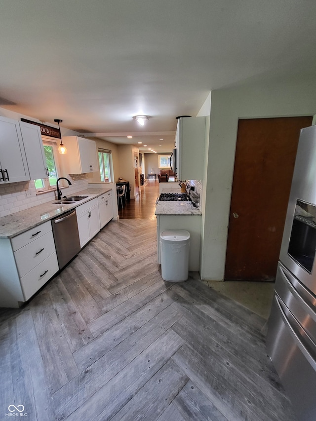 kitchen with sink, white cabinets, parquet floors, and backsplash