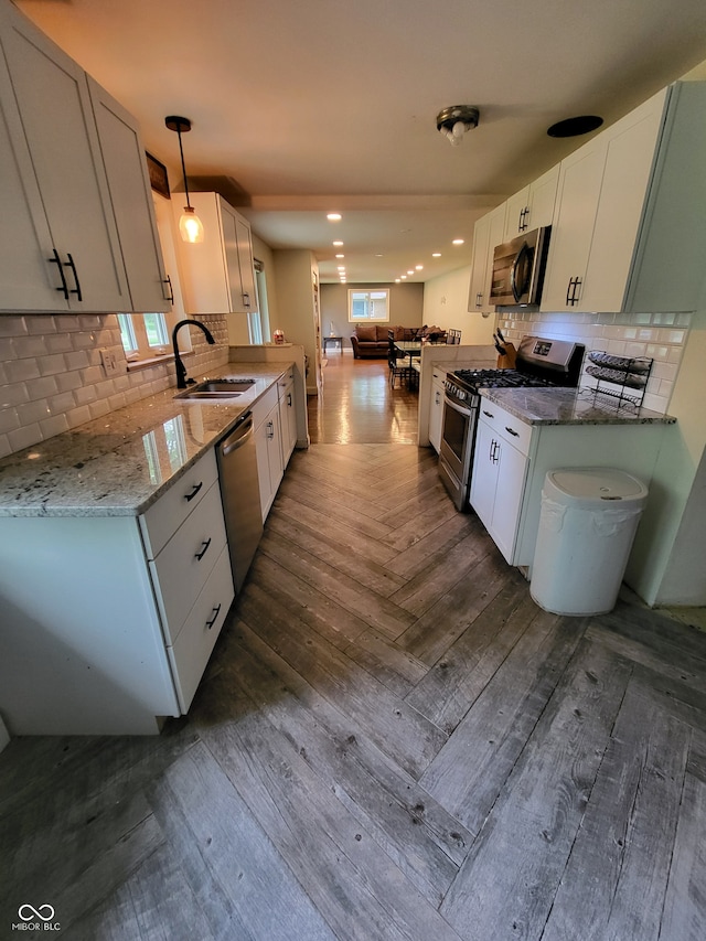 kitchen with appliances with stainless steel finishes, parquet flooring, decorative light fixtures, backsplash, and sink