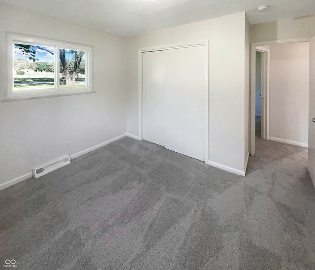 unfurnished bedroom with a closet and dark carpet