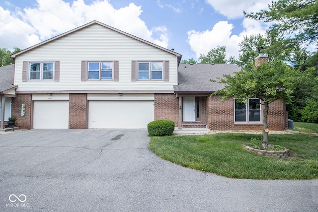 2424 N Willow Way, Indianapolis, IN 46268 - view of front of home featuring brick siding, a garage, driveway, a front lawn, and roof with shingles