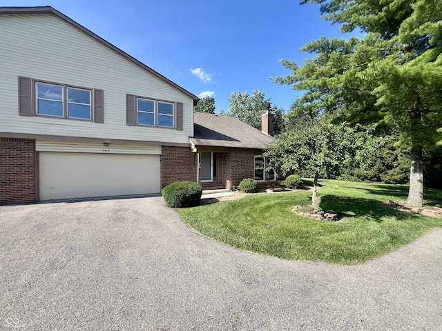 2424 N Willow Way, Indianapolis, IN 46268 - view of front facade featuring brick siding, asphalt driveway, a chimney, a front lawn, and an attached garage