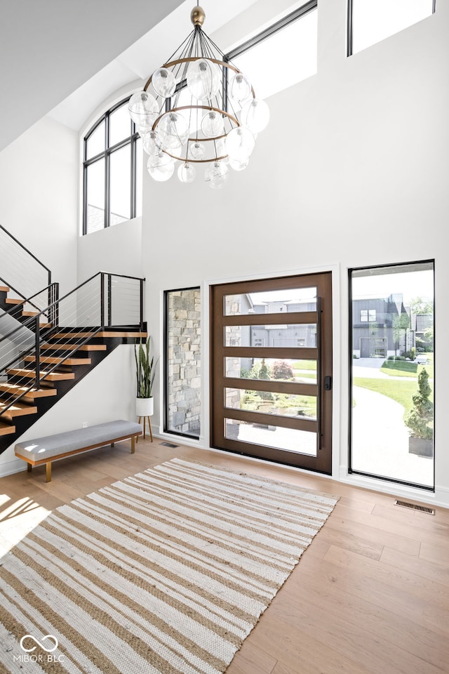 foyer entrance featuring light wood-type flooring, a high ceiling, and an inviting chandelier