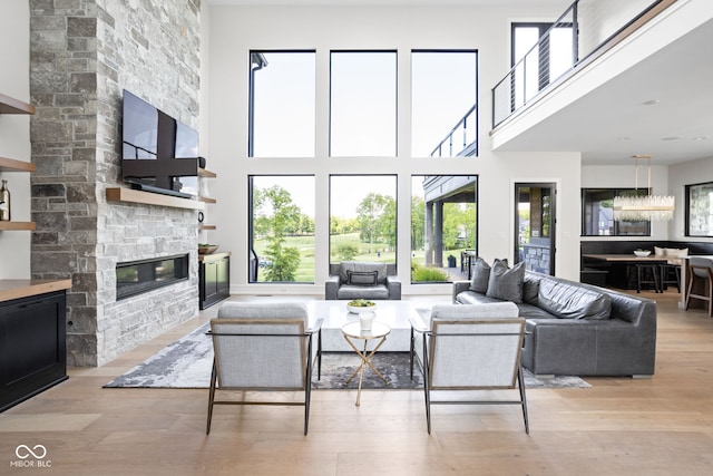 living room featuring light hardwood / wood-style floors, a stone fireplace, and a towering ceiling