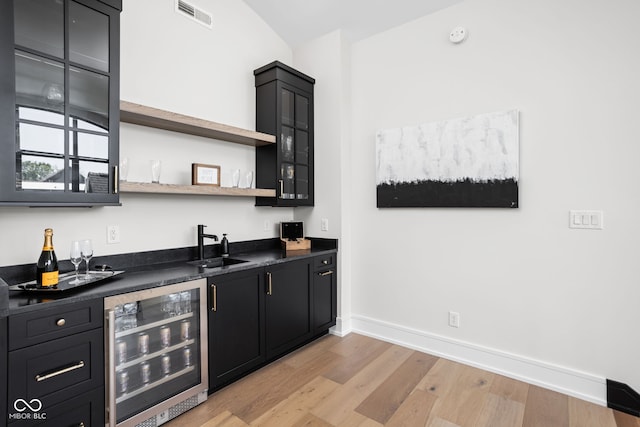 bar featuring light hardwood / wood-style floors, sink, and wine cooler