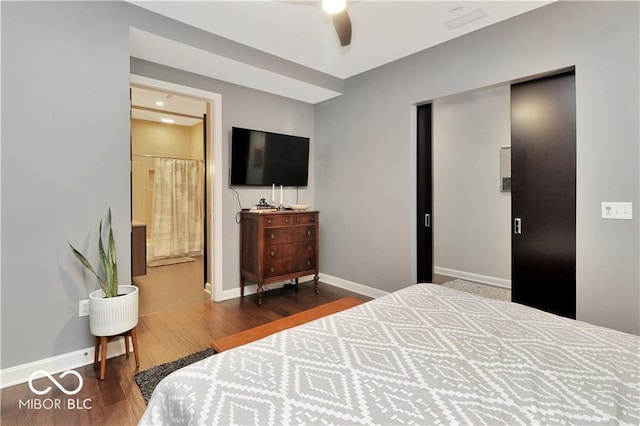 bedroom featuring dark hardwood / wood-style floors, ceiling fan, and ensuite bathroom