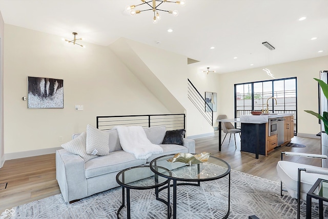 living room with light hardwood / wood-style flooring, a notable chandelier, and sink