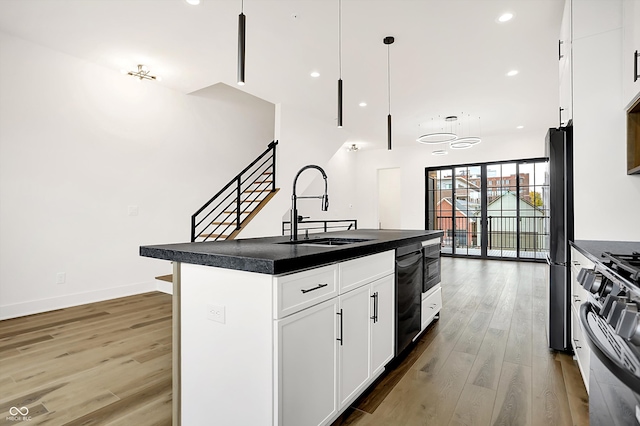 kitchen featuring white cabinets, sink, hanging light fixtures, dark hardwood / wood-style floors, and an island with sink