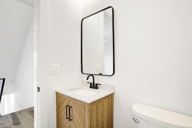 bathroom with hardwood / wood-style floors, vanity, and toilet