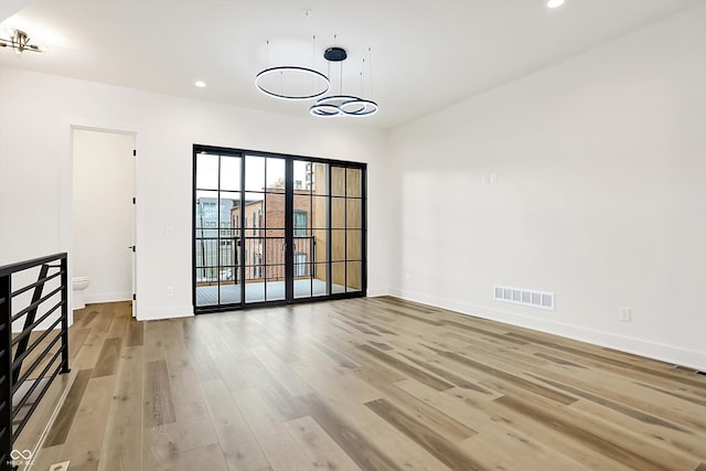 empty room with hardwood / wood-style flooring and an inviting chandelier