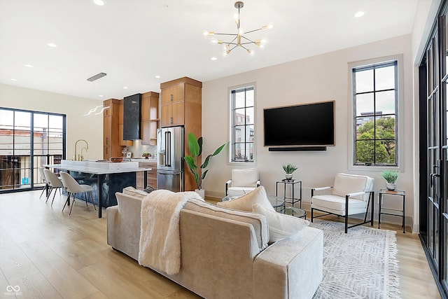 living room featuring plenty of natural light, light hardwood / wood-style floors, and a chandelier