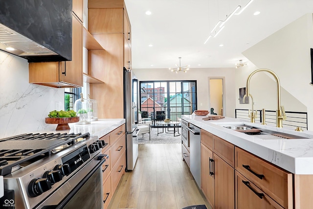 kitchen with stainless steel appliances, sink, light hardwood / wood-style flooring, a notable chandelier, and range hood