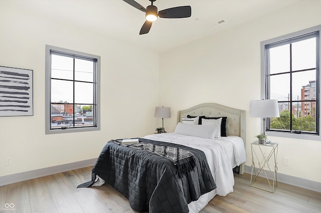 bedroom with multiple windows, light hardwood / wood-style floors, and ceiling fan