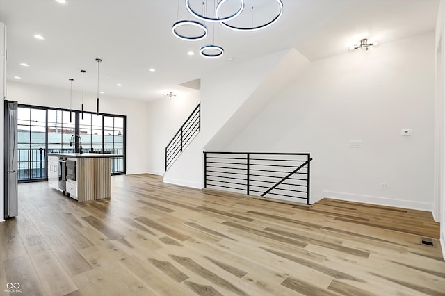 unfurnished living room with light hardwood / wood-style flooring and sink