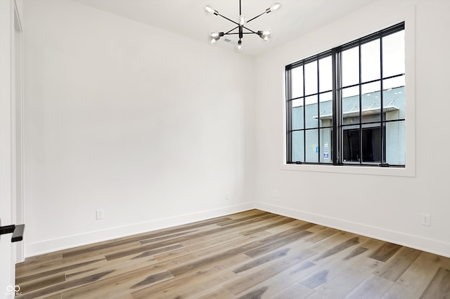 unfurnished room featuring hardwood / wood-style floors and a chandelier