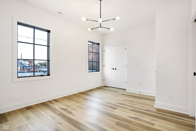 spare room with light hardwood / wood-style flooring and a notable chandelier