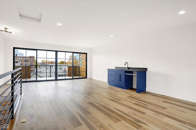 unfurnished living room with light hardwood / wood-style flooring and sink