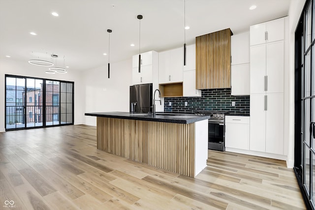 kitchen with hanging light fixtures, white cabinetry, an island with sink, and appliances with stainless steel finishes