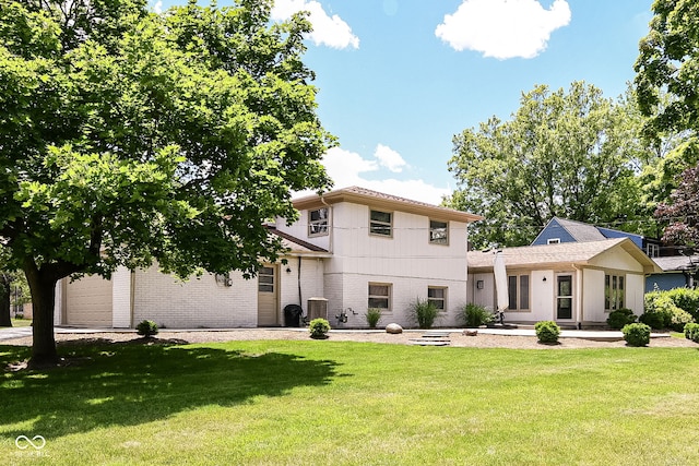 view of front of property featuring a front yard, a garage, and central AC