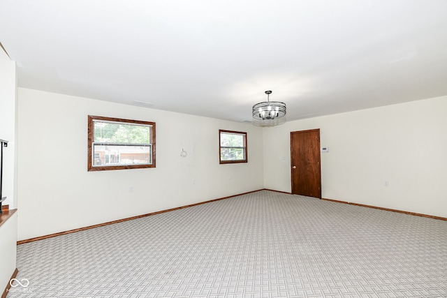 carpeted spare room featuring a wealth of natural light and a chandelier