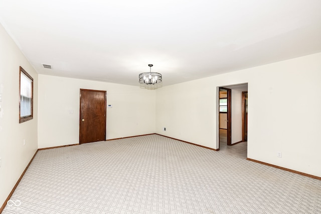 carpeted spare room with an inviting chandelier