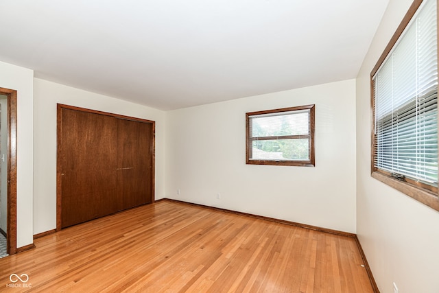 unfurnished bedroom with light wood-type flooring and a closet