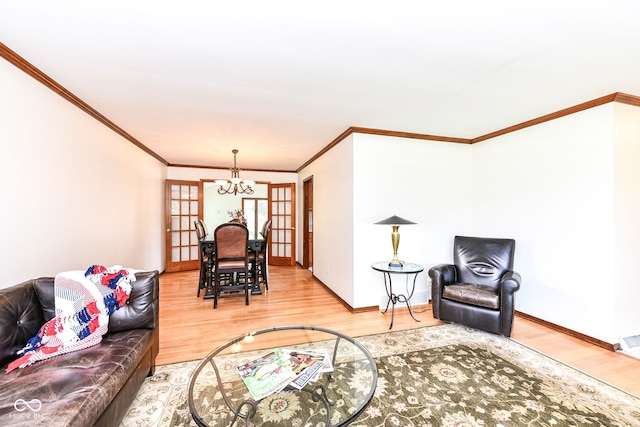 living room with hardwood / wood-style flooring, french doors, crown molding, and a chandelier