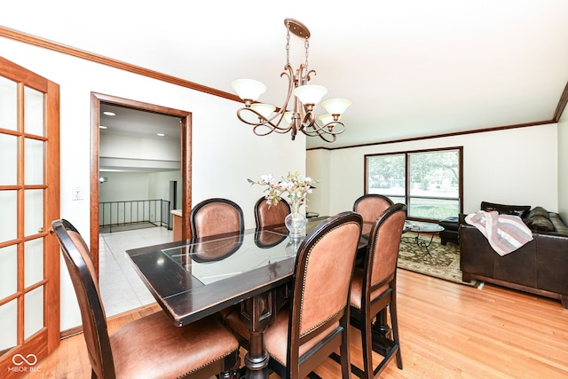 dining room featuring ornamental molding, light wood-type flooring, and a chandelier