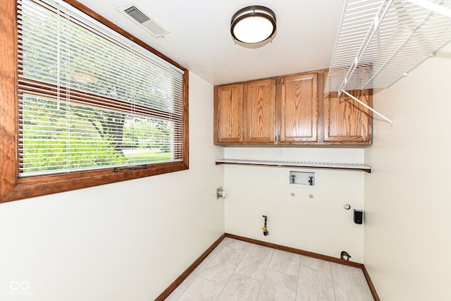 laundry area with cabinets, hookup for a washing machine, hookup for a gas dryer, hookup for an electric dryer, and light tile patterned floors