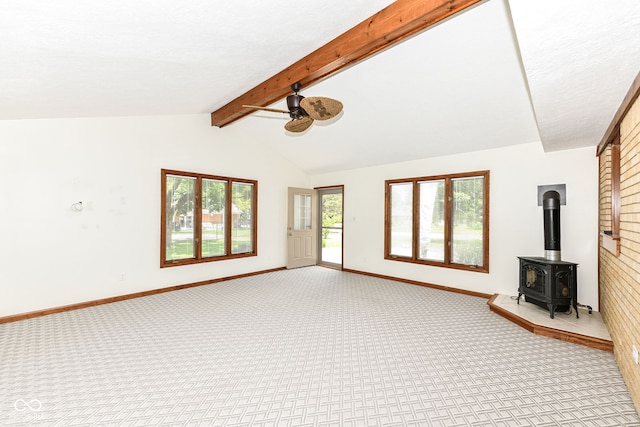 unfurnished living room with ceiling fan, light colored carpet, lofted ceiling with beams, and a wood stove