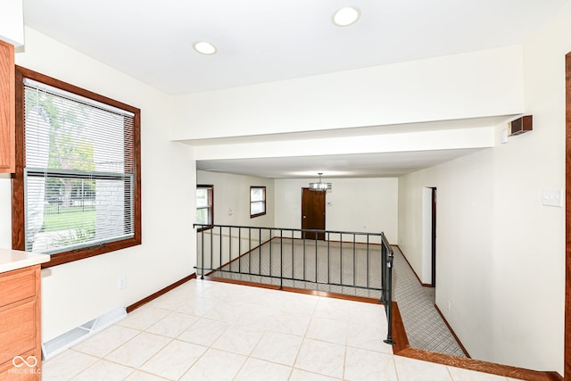 corridor featuring light tile patterned flooring and a chandelier