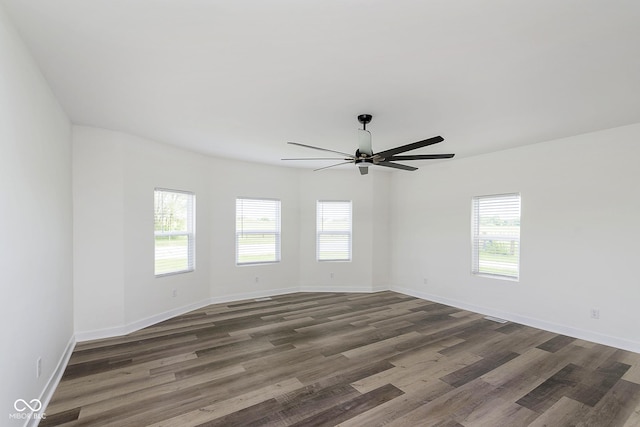 empty room with ceiling fan, dark hardwood / wood-style floors, and a wealth of natural light