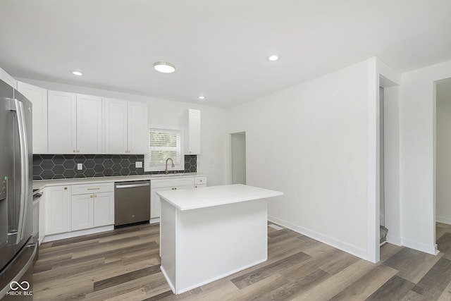 kitchen featuring a kitchen island, wood-type flooring, sink, white cabinetry, and appliances with stainless steel finishes