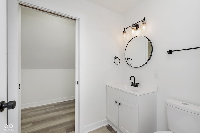 bathroom with toilet, vanity, and hardwood / wood-style floors