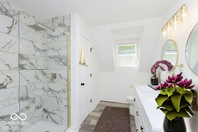 bathroom with toilet, vanity, tiled shower, and hardwood / wood-style flooring