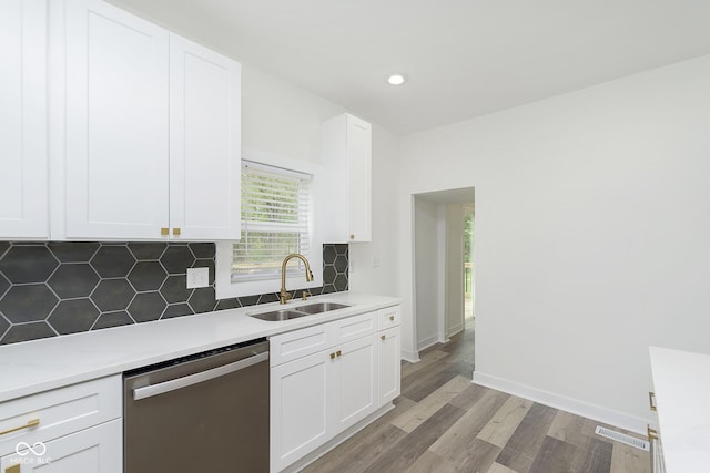 kitchen with white cabinets, dishwasher, tasteful backsplash, sink, and light hardwood / wood-style flooring