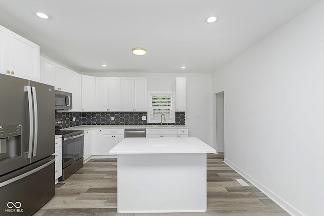 kitchen featuring light hardwood / wood-style floors, stainless steel appliances, a kitchen island, white cabinets, and sink