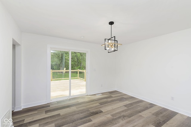 unfurnished dining area with hardwood / wood-style flooring and a notable chandelier