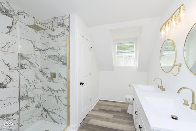 bathroom featuring hardwood / wood-style flooring, toilet, tiled shower, and vanity