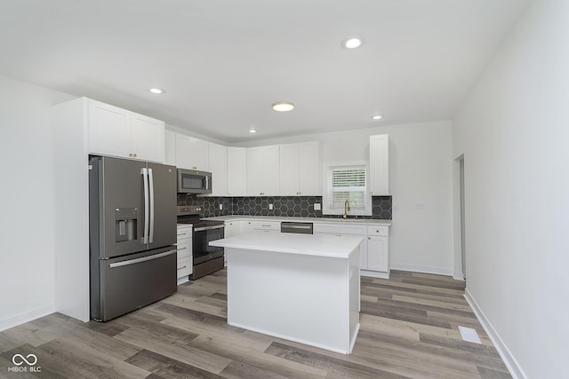 kitchen featuring white cabinets, light hardwood / wood-style floors, stainless steel appliances, and a center island