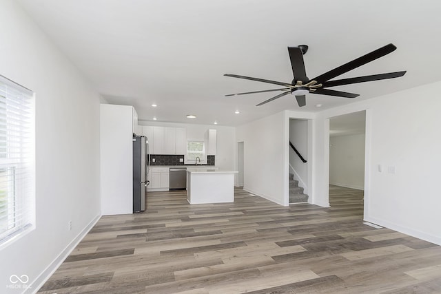 unfurnished living room with ceiling fan, sink, and light hardwood / wood-style flooring