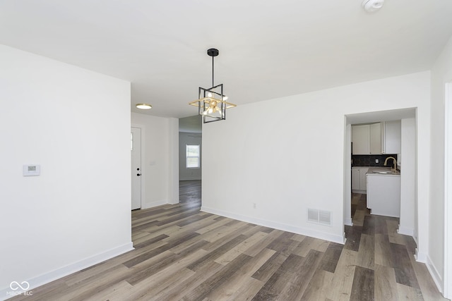 unfurnished room featuring dark hardwood / wood-style flooring, sink, and an inviting chandelier