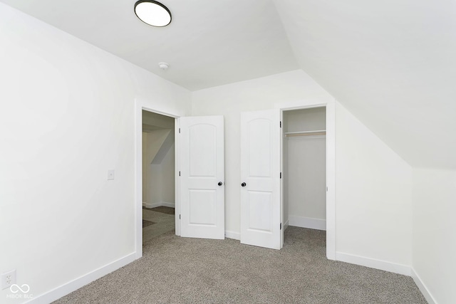 unfurnished bedroom featuring light carpet, a closet, and lofted ceiling