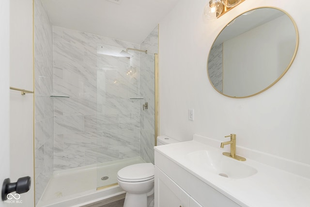 bathroom featuring toilet, a tile shower, and vanity