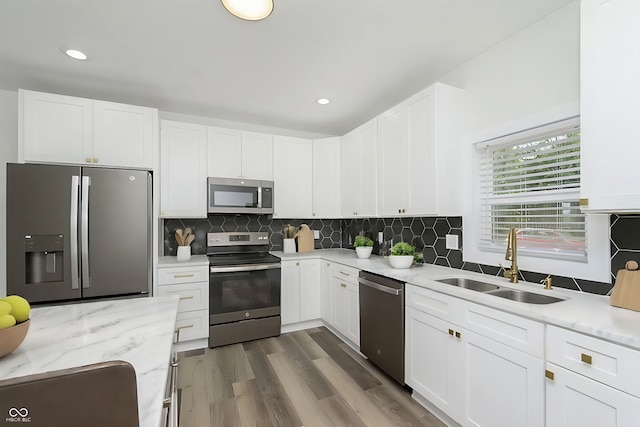 kitchen featuring appliances with stainless steel finishes, wood-type flooring, white cabinets, and sink