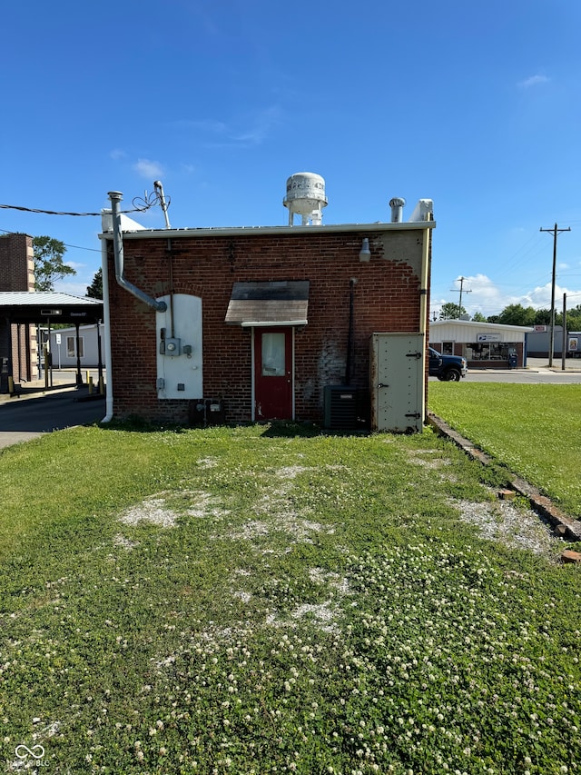 rear view of property featuring a yard and cooling unit