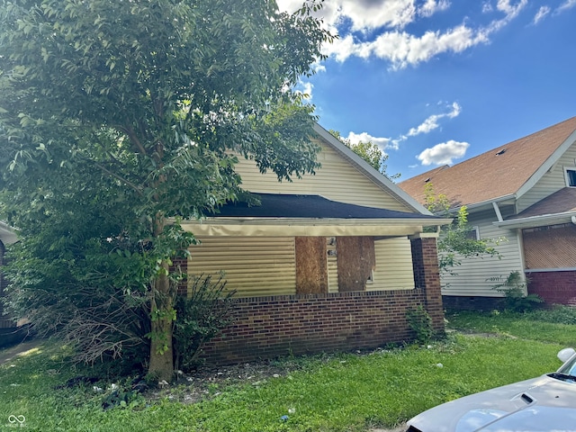 view of side of property with brick siding and a lawn