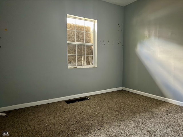 empty room featuring carpet floors, visible vents, and baseboards